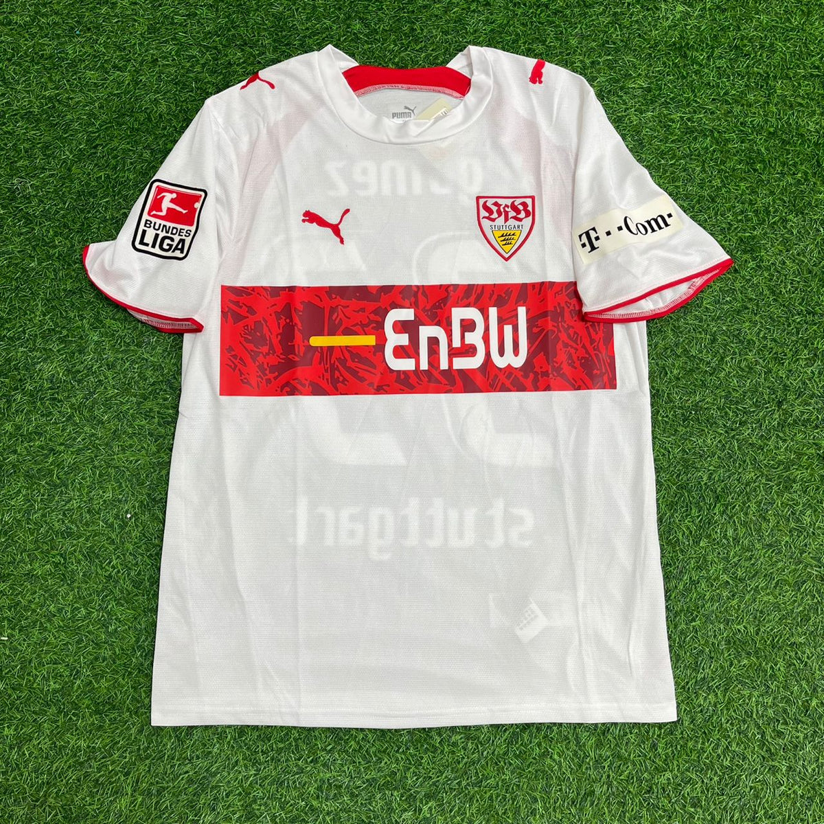 White sports jersey with red and black details on a green grass background